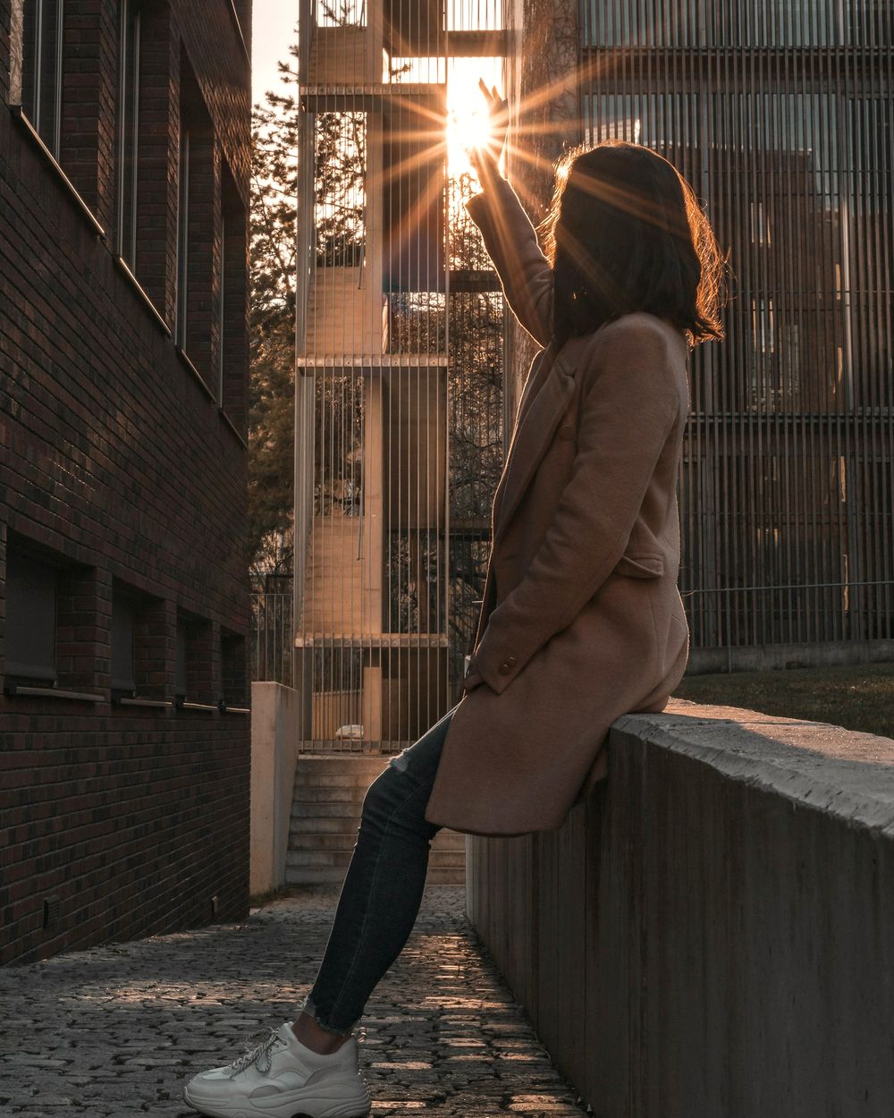 Una donna seduta su un muretto, in controluce nel sole del tramonto