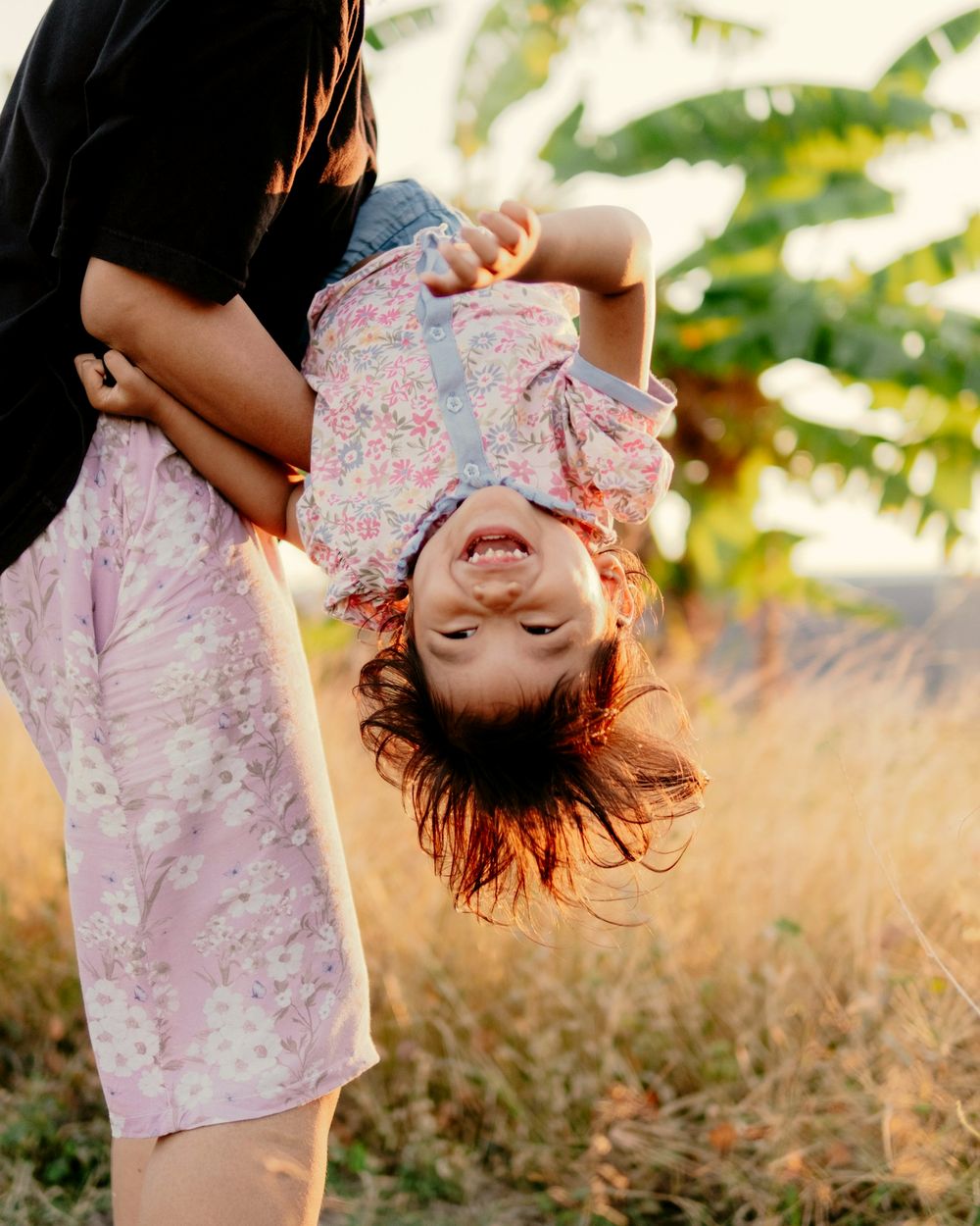 Una mamma tiene la sua bambina a testa in giù: la bambina ride